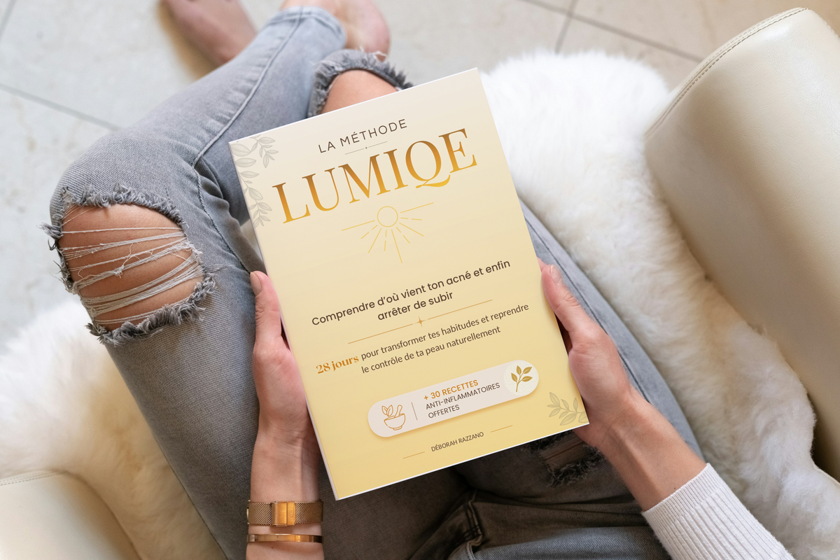 La méthode LUMIQE tenue entre les mains, posée sur les genoux dans un fauteuil clair